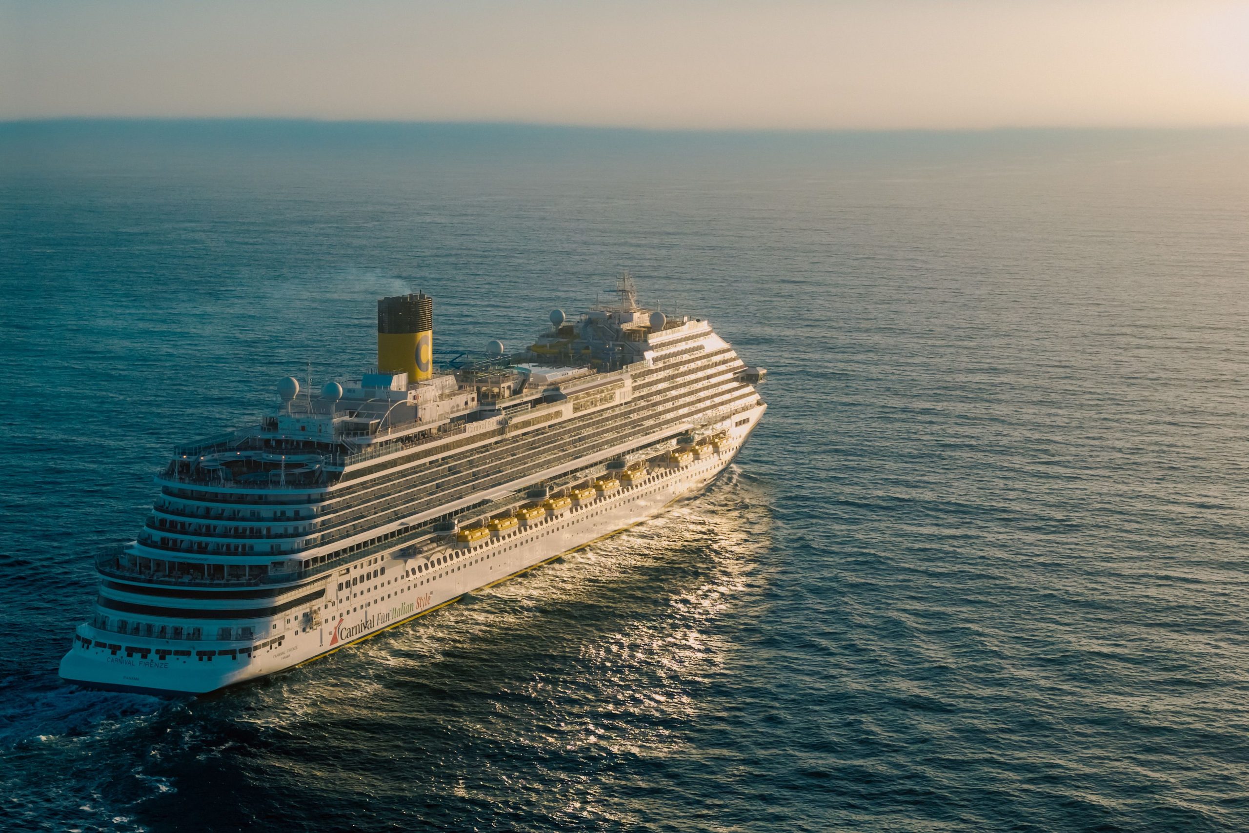 Cruise ship sailing across the ocean at sunset, illustrating a fall 2026 cruise vacation