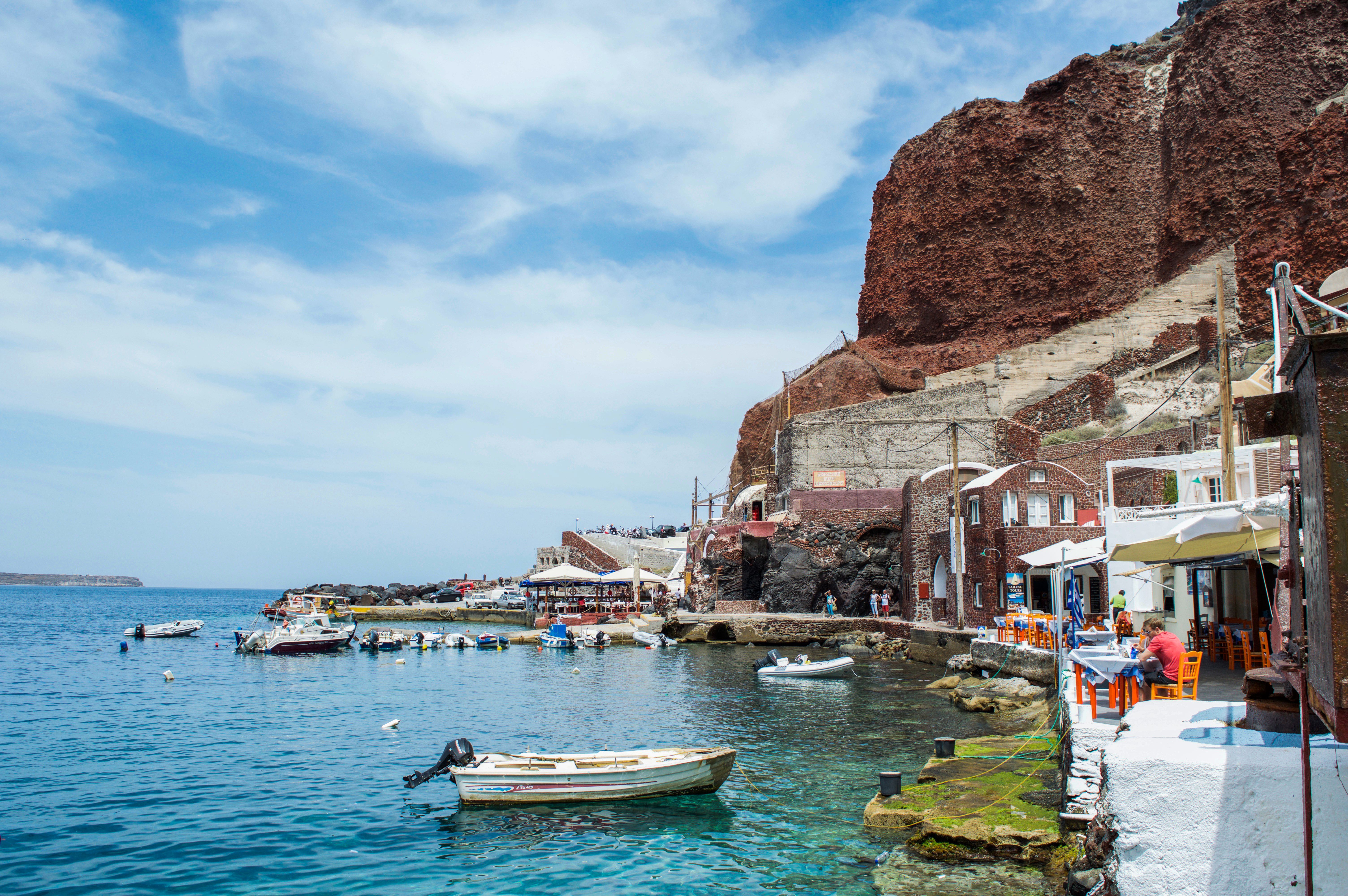 Santorini harbor with boats and whitewashed buildings on a Greek islands cruise